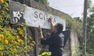 Padre Giuseppe Cicala riscrive i cartelli stradali per segnalare la frazione di Sciara